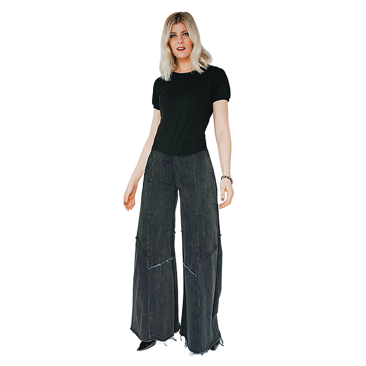 model in Alex Jean in Black – low-rise wide-leg upcycled denim jeans with raw hem and fading, shown in worn black wash.