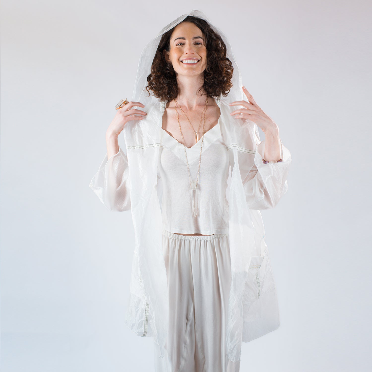 model in Sheer hooded knee-length parachute coat with pockets, unlined design, and visible seamlines from original upcycled nylon.