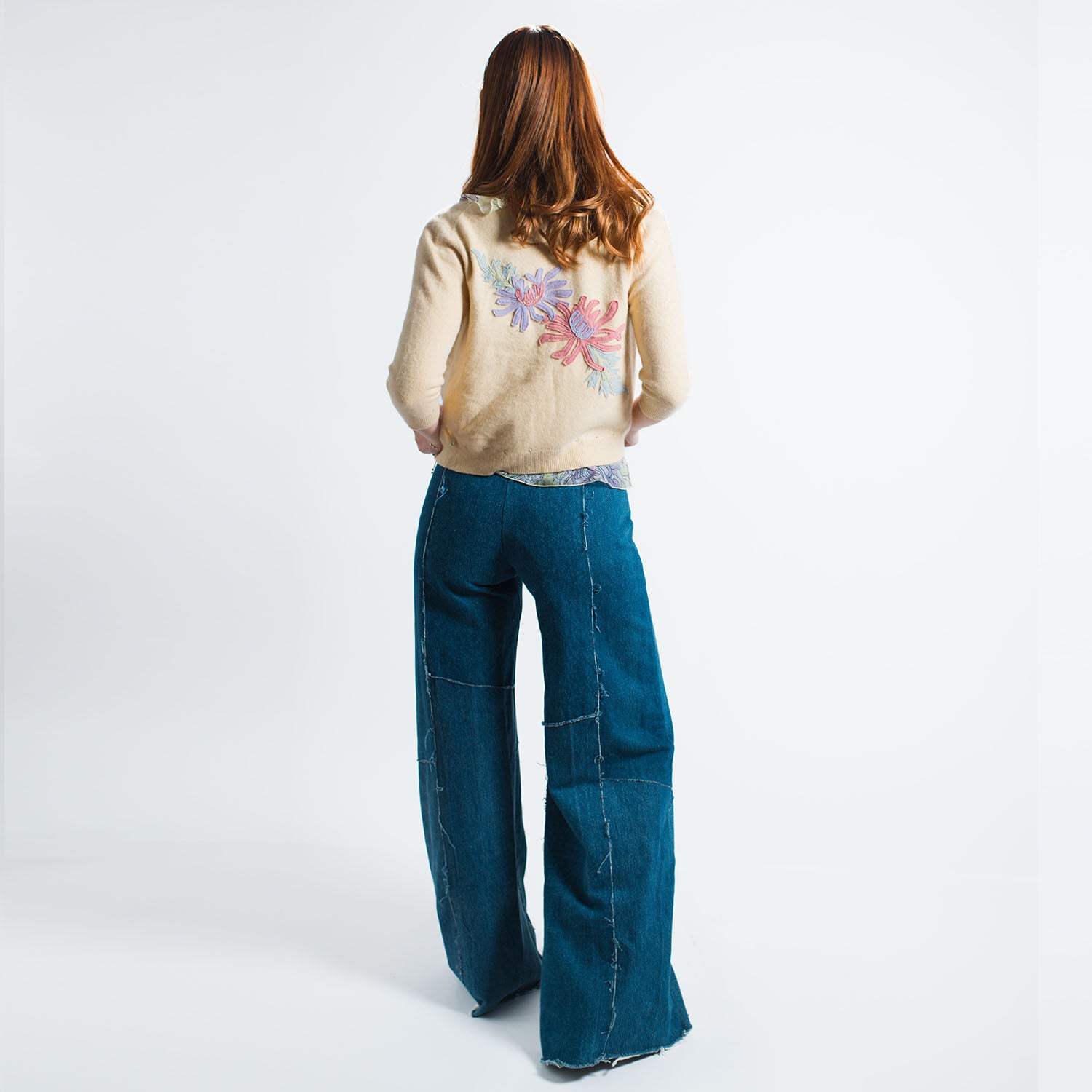 model in Alex Jean in Medium Blue – wide-leg low-rise upcycled denim jeans with fly front and raw hem, shown in soft indigo wash.