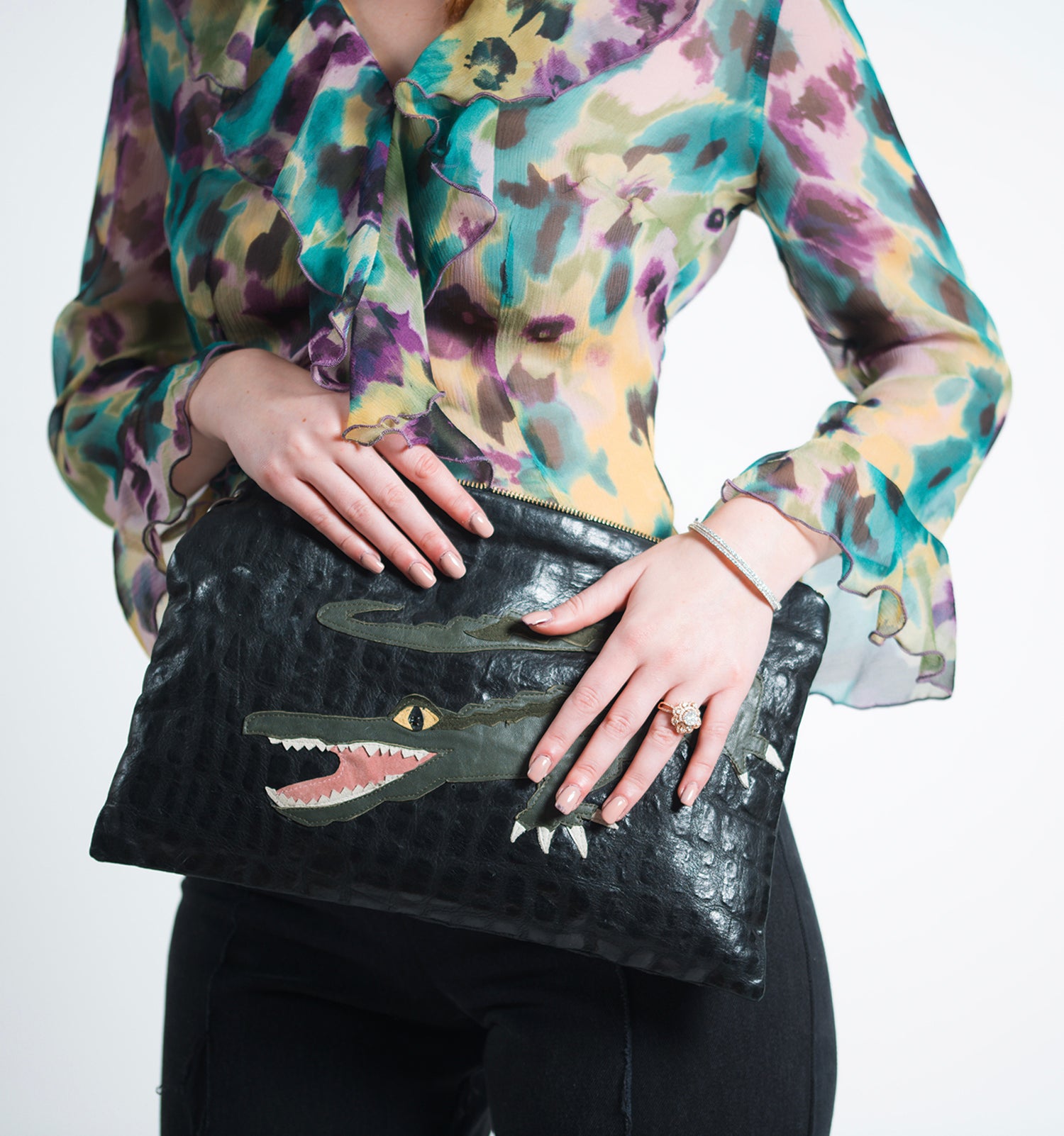 Upcycled black leather clutch bag with textured finish and appliquéd alligator featuring rhinestone eyes