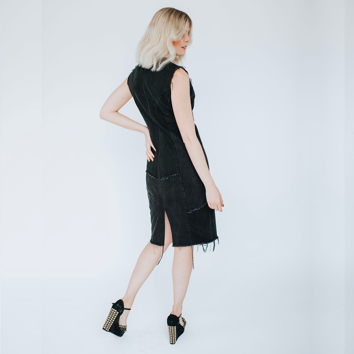 model in Blair Dress – fitted studded black denim dress with raw-edge hem, antique brass studs, and exposed metal zipper,