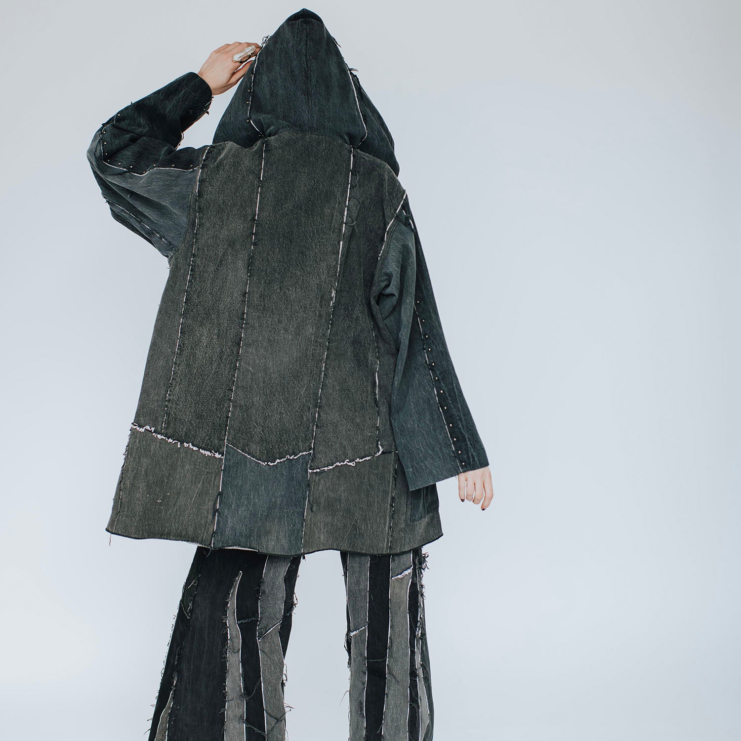 back Oversized hooded black denim coat with raw-edge seams and a deconstructed silhouette.