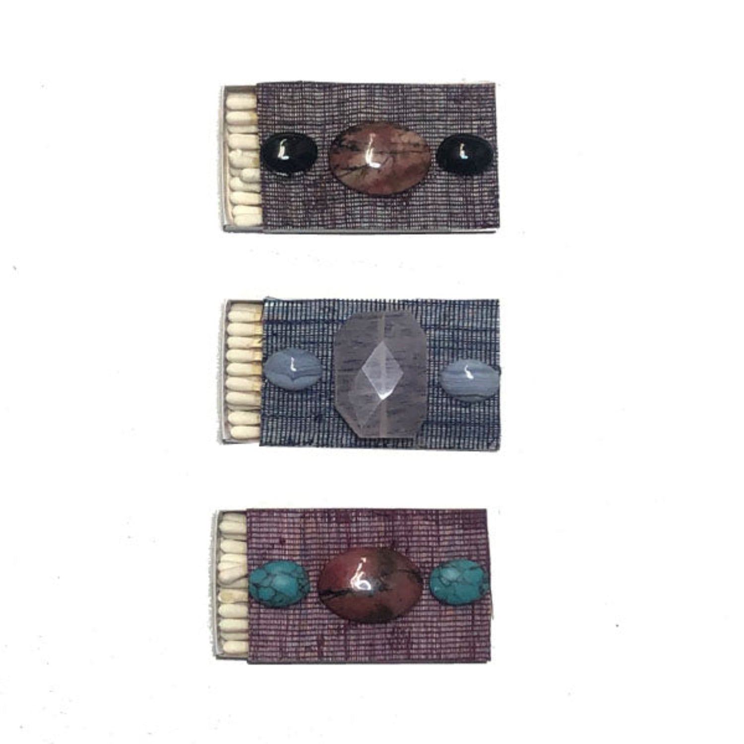 Three matchboxes with decorative designs on a white background