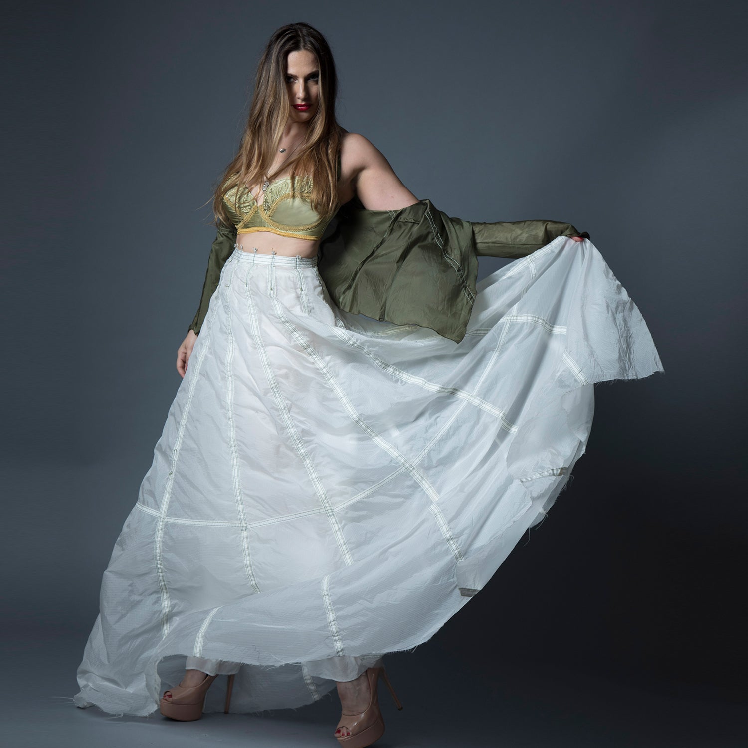 model in Olivia Parachute Skirt in white, gored-panel design with flared hem, made from lightweight upcycled military nylon with original seamline details”