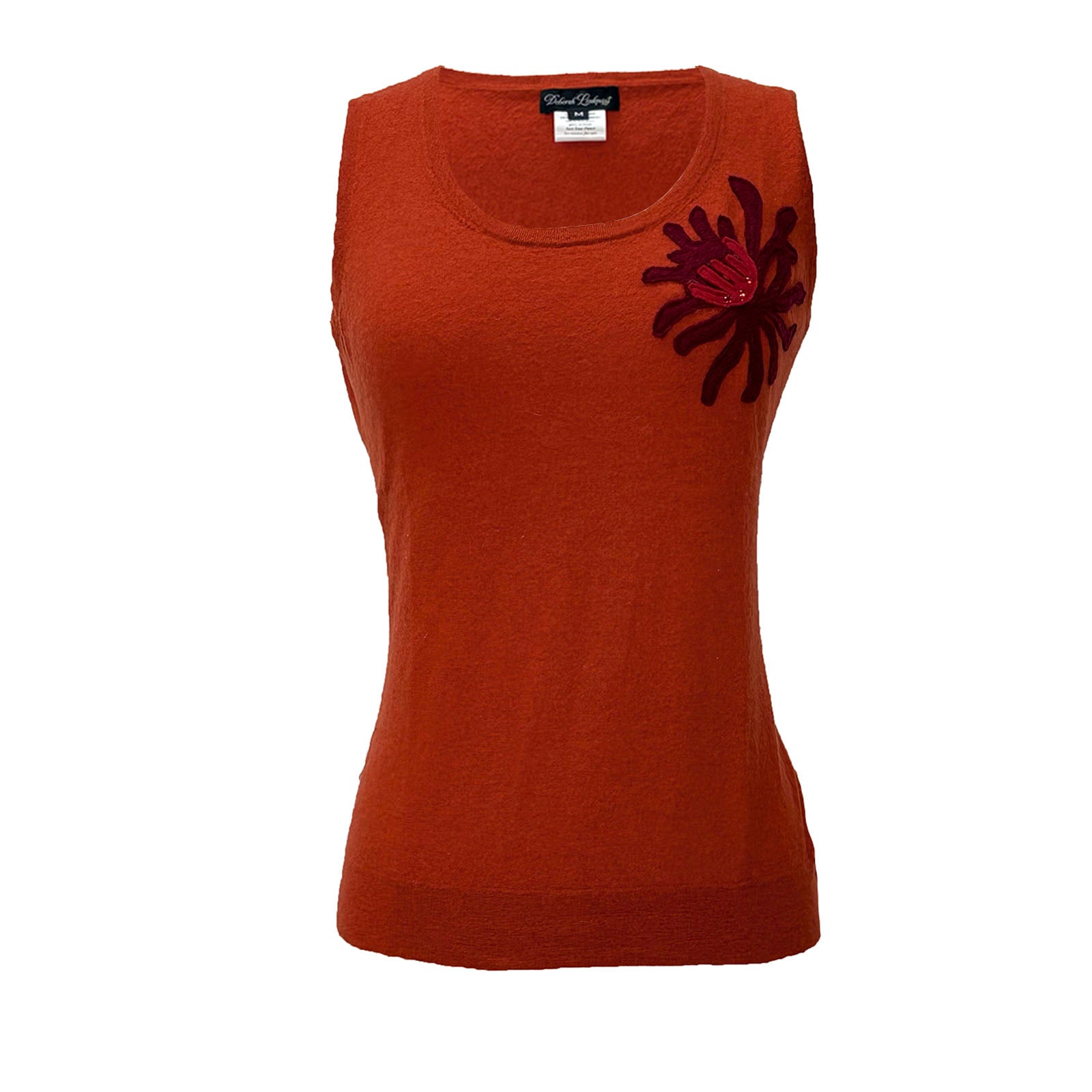 Sleeveless burnt orange cashmere sweater with dark red chrysanthemum corsage appliqué on the shoulder.