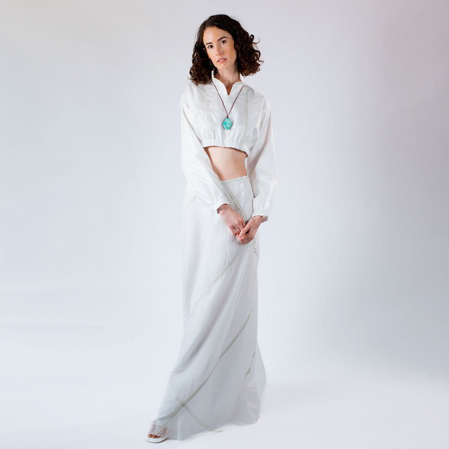 Model wearing a cropped white bomber jacket crafted from retired military parachutes styled with the adrienne parachute skirt