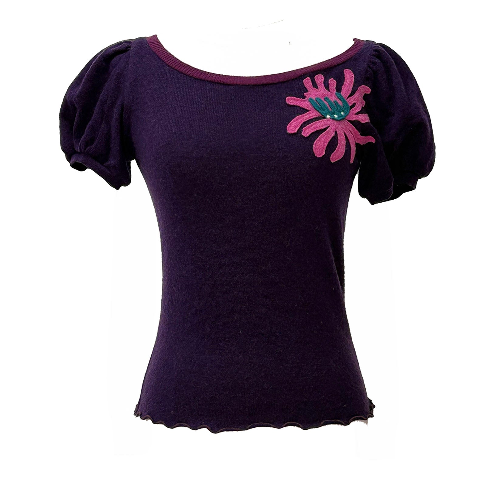 Plum cashmere corsage sweater with gathered sleeves and pink floral appliqué on the shoulder, styled as an everyday statement piece.