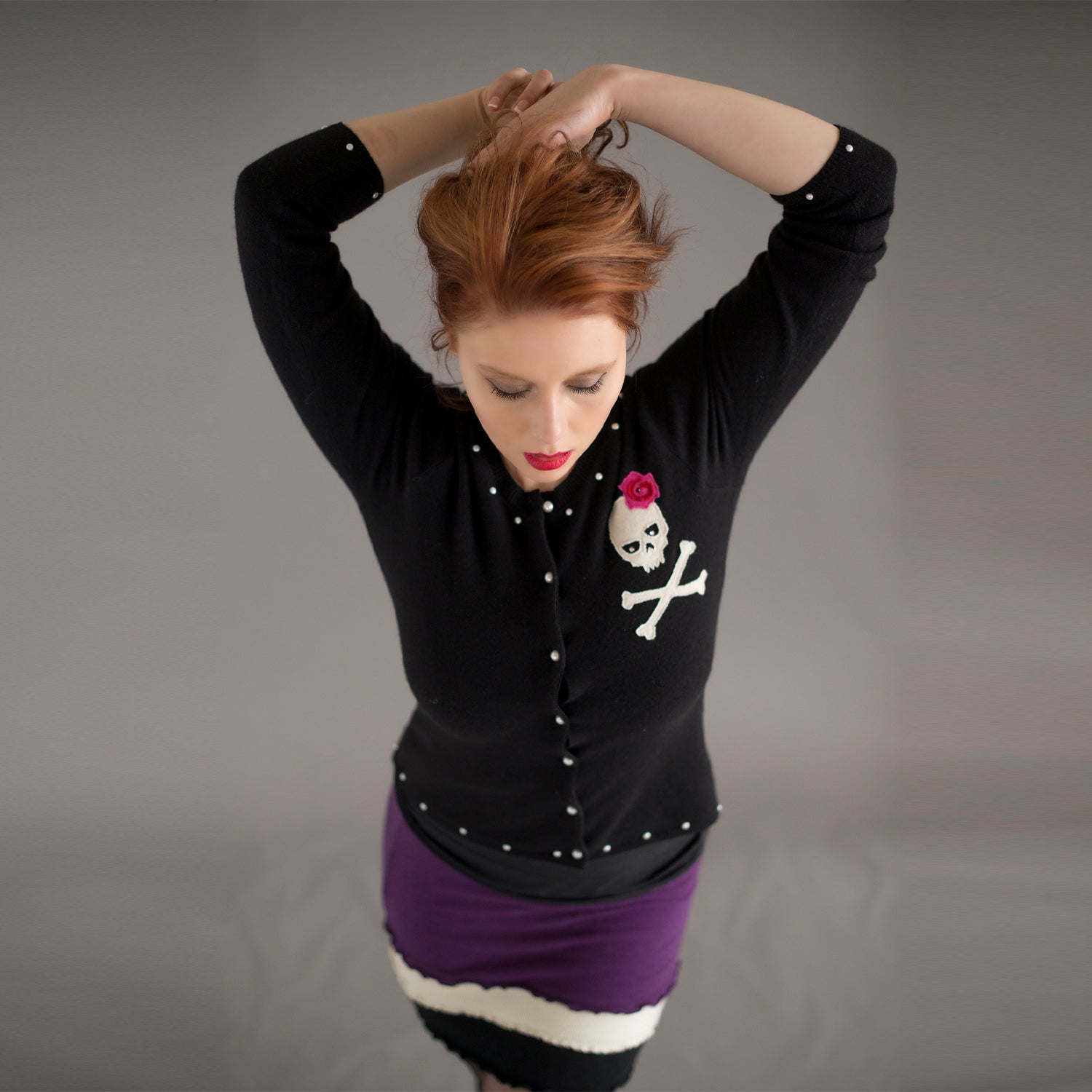 model Skull Cardigan in black reincarnated cashmere with skull and rose appliqué, pearl buttons, and pearl studs
