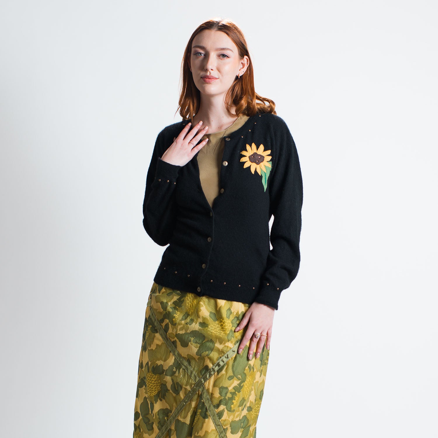 model; Sunflower Cardigan in black upcycled cashmere with floral appliqué at front chest, metal buttons and brass studs