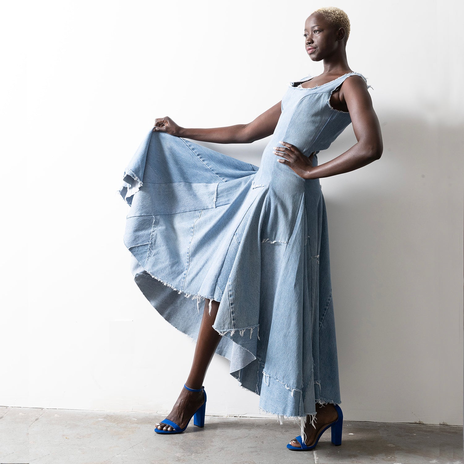 Valerie Dress in bleached denim – model in high-low hem dress with dramatic movement and raw-edged finish.