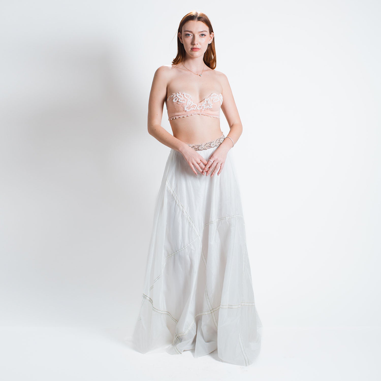 model Flowing white parachute skirt in a half-circle silhouette with subtle seam details; crafted from lightweight upcycled military nylon.