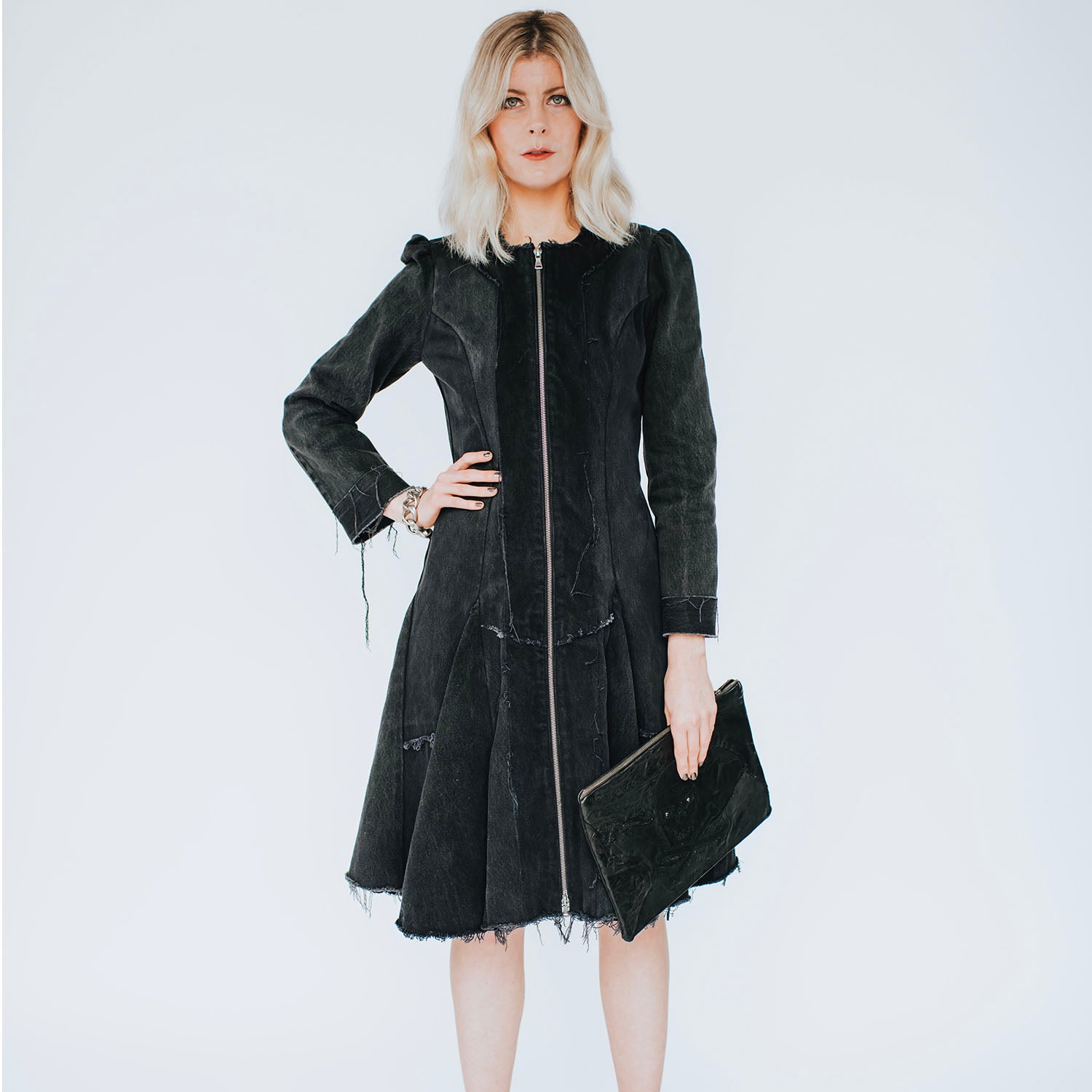 model in Front view of the Zelda Coat in distressed black denim featuring a fit-and-flare silhouette with raw-edged detailing and a full-length zipper closure.