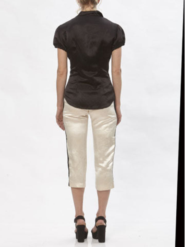 Model wearing cream hemp silk cigarette pants with black contrast side stripe and cropped hem, paired with black short-sleeve blouse.
