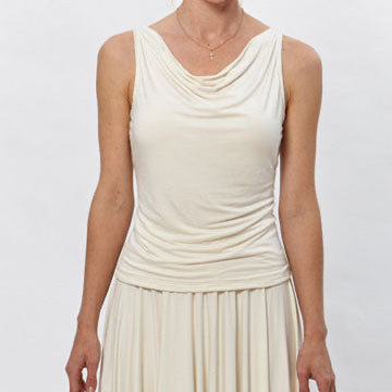 Model wearing the River Cowl Top by Deborah Lindquist, a sleeveless ivory modal knit top with a softly draped cowl neckline paired with a flowing asymmetrical skirt. Sustainably made in Los Angeles.