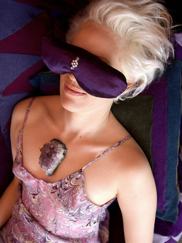 Woman relaxing with a purple hemp and silk aromatherapy eye pillow with third-eye bindi accent.