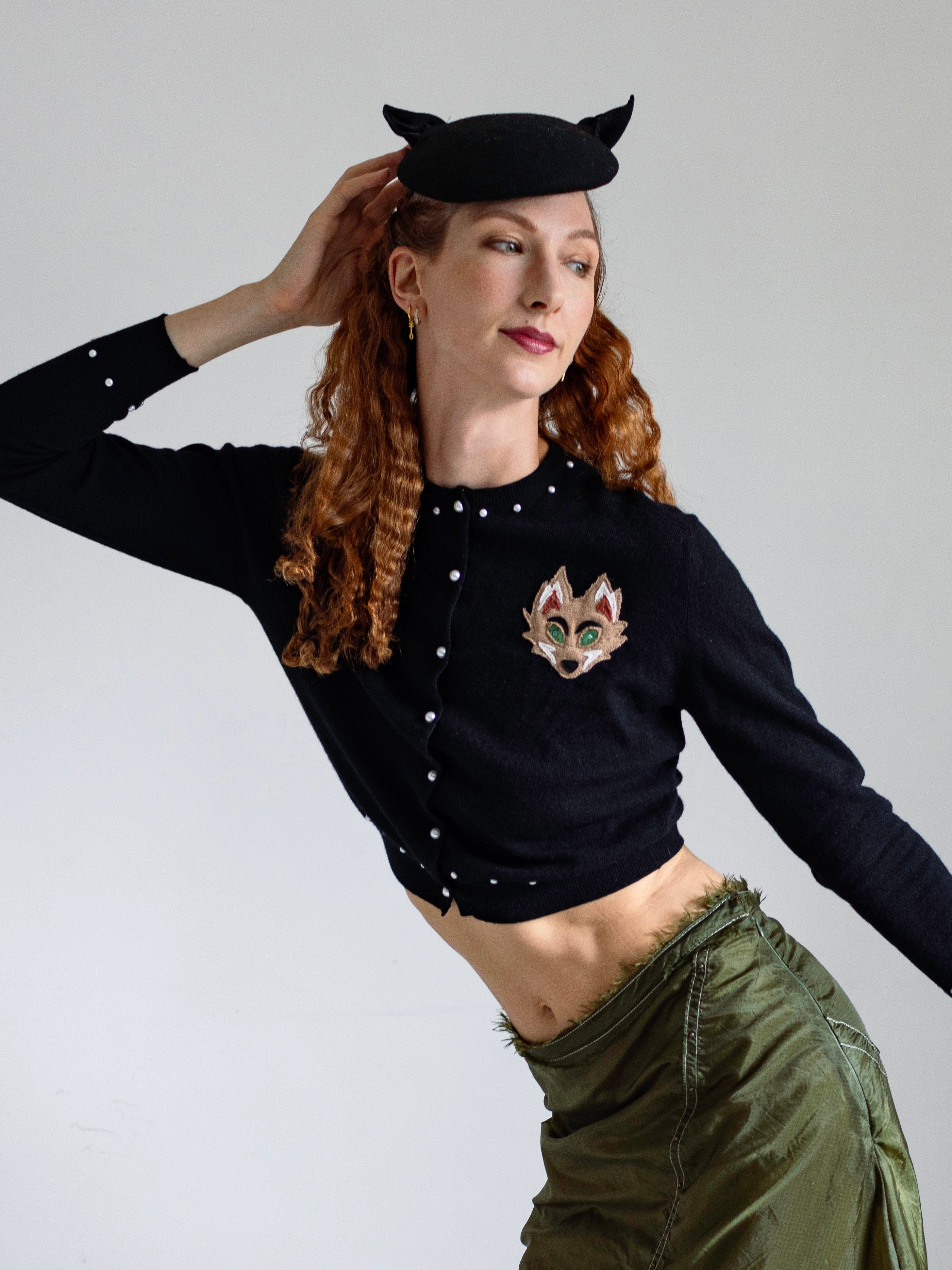 Fox Cardigan in black upcycled cashmere with front fox appliqué, pearl buttons, and rhinestone embellishments, cropped version on model.