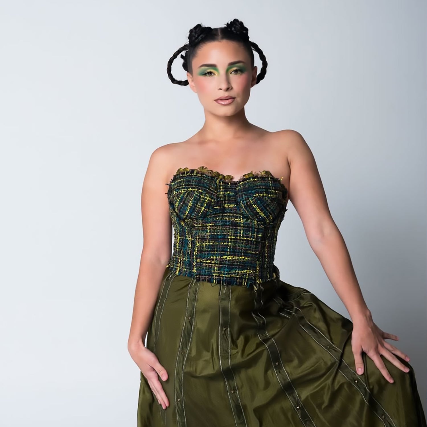 Model wearing a one-of-a-kind olive and black vintage silk tweed bustier with feather trim paired with a flowing studded Olivia skirt