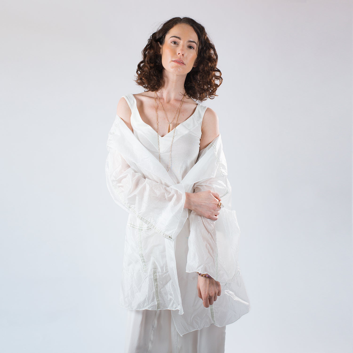 model in Sheer hooded knee-length parachute coat with pockets, unlined design, and visible seamlines from original upcycled nylon.