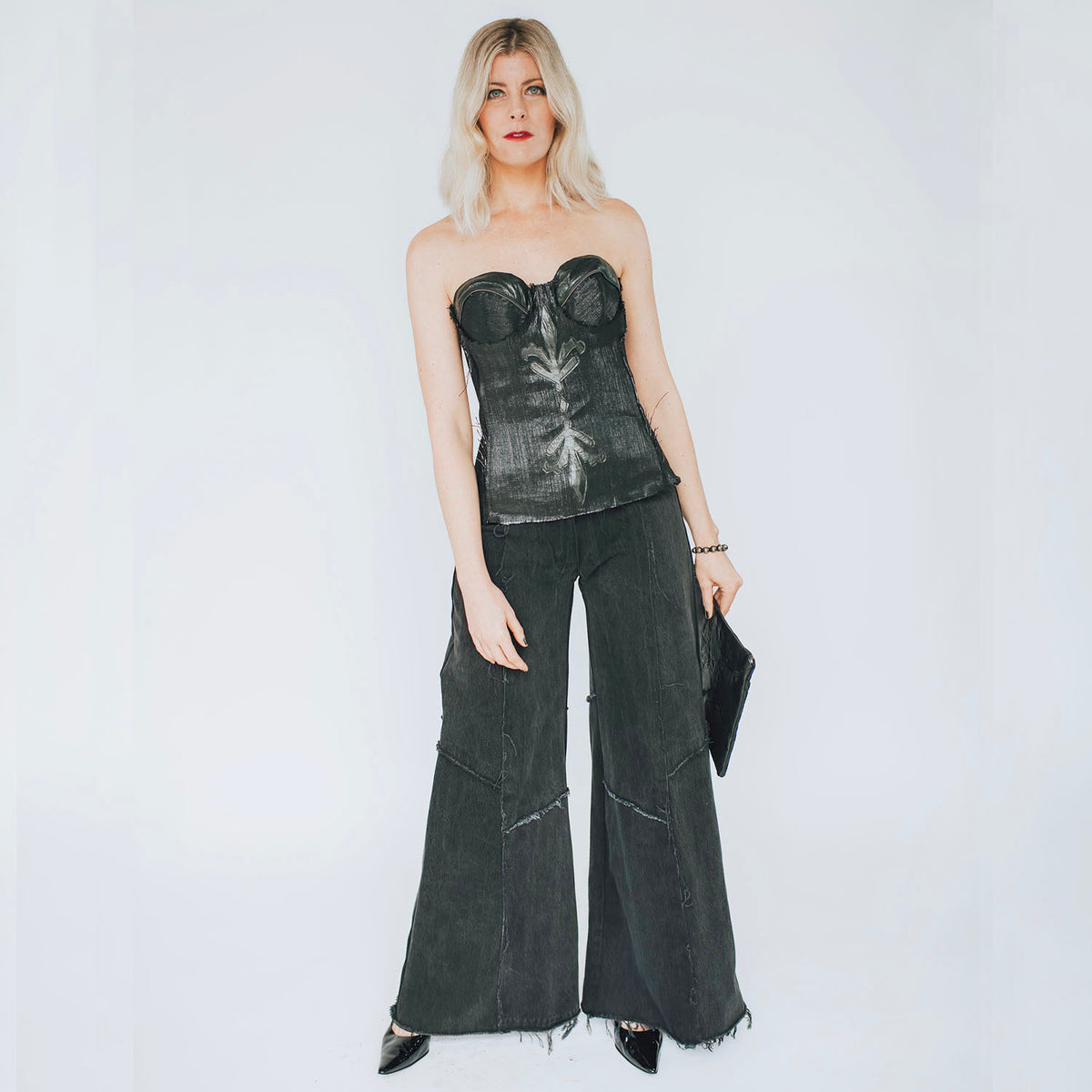 model in Alex Jean in Black – low-rise wide-leg upcycled denim jeans with raw hem and fading, shown in worn black wash.