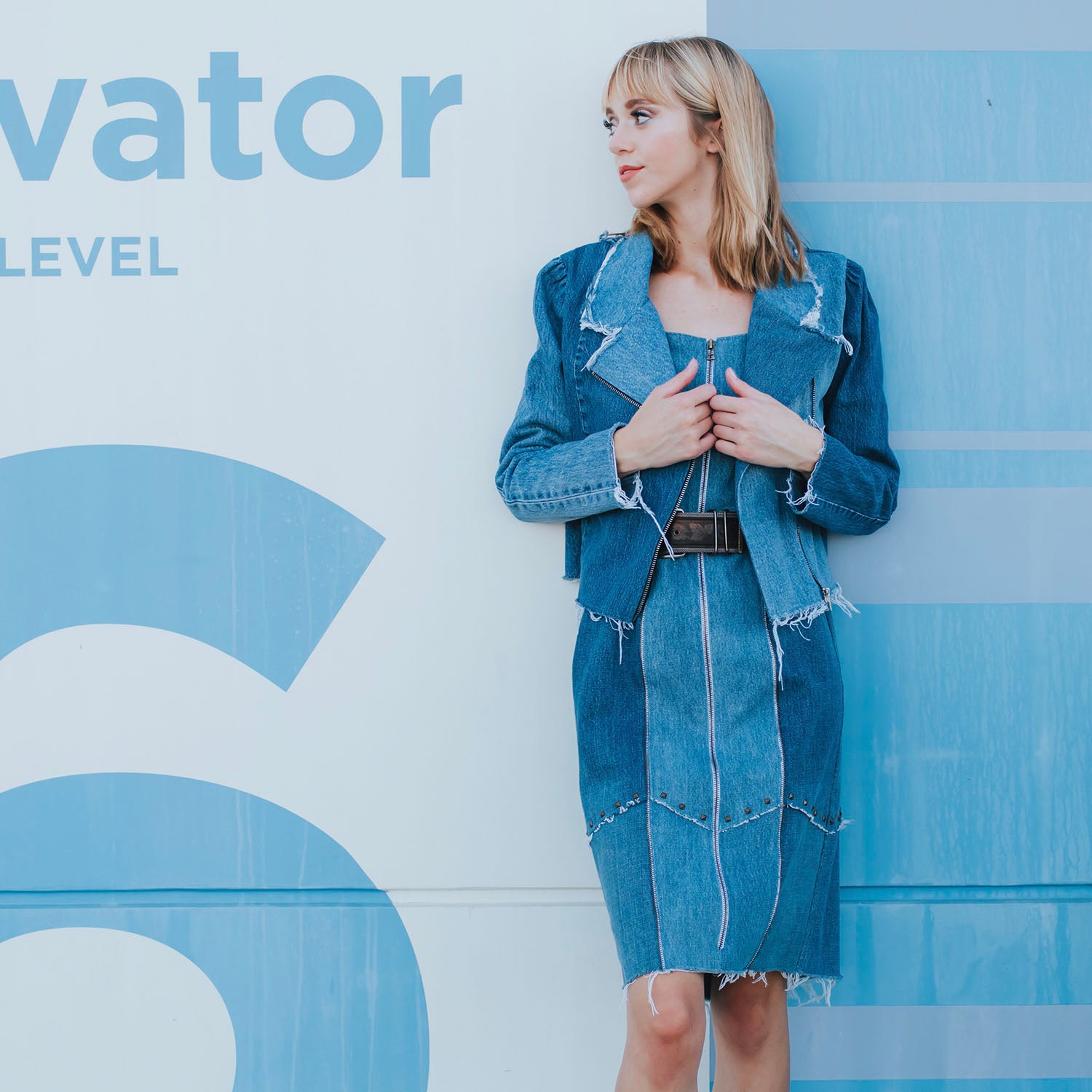 model in Medium blue upcycled denim motorcycle jacket with raw edges and metal zip. A timeless, sustainable staple reimagined with edge.