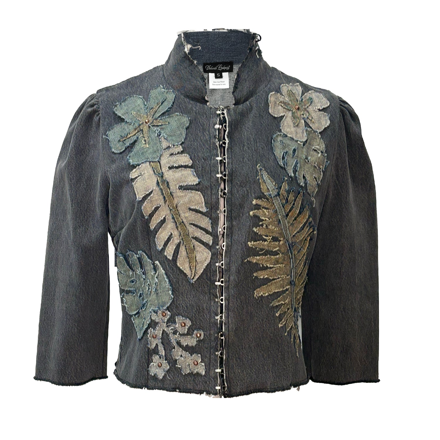 A cropped denim jacket with tropical floral and leaf appliqué embellishments, featuring a mandarin collar and hook front closure.