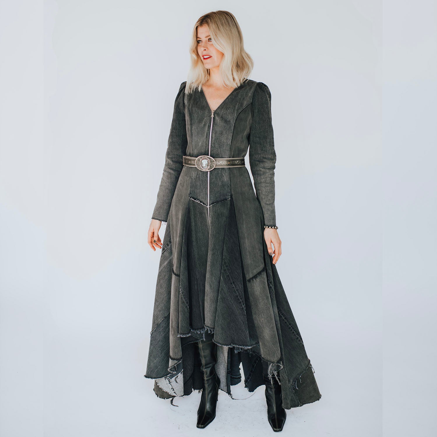 model in Front view of the Beatrix Coat in distressed black upcycled denim featuring a high-low hem, raw edges, V-neckline, and exposed double zipper closure.