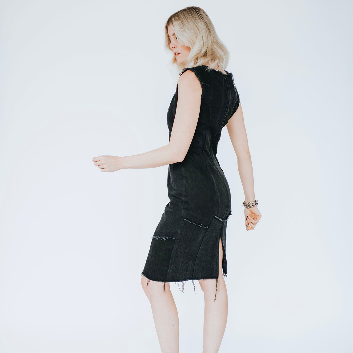 Bettina Dress – fitted little black dress in upcycled denim with raw edges and metal back zipper, shown on model with frayed hem.
