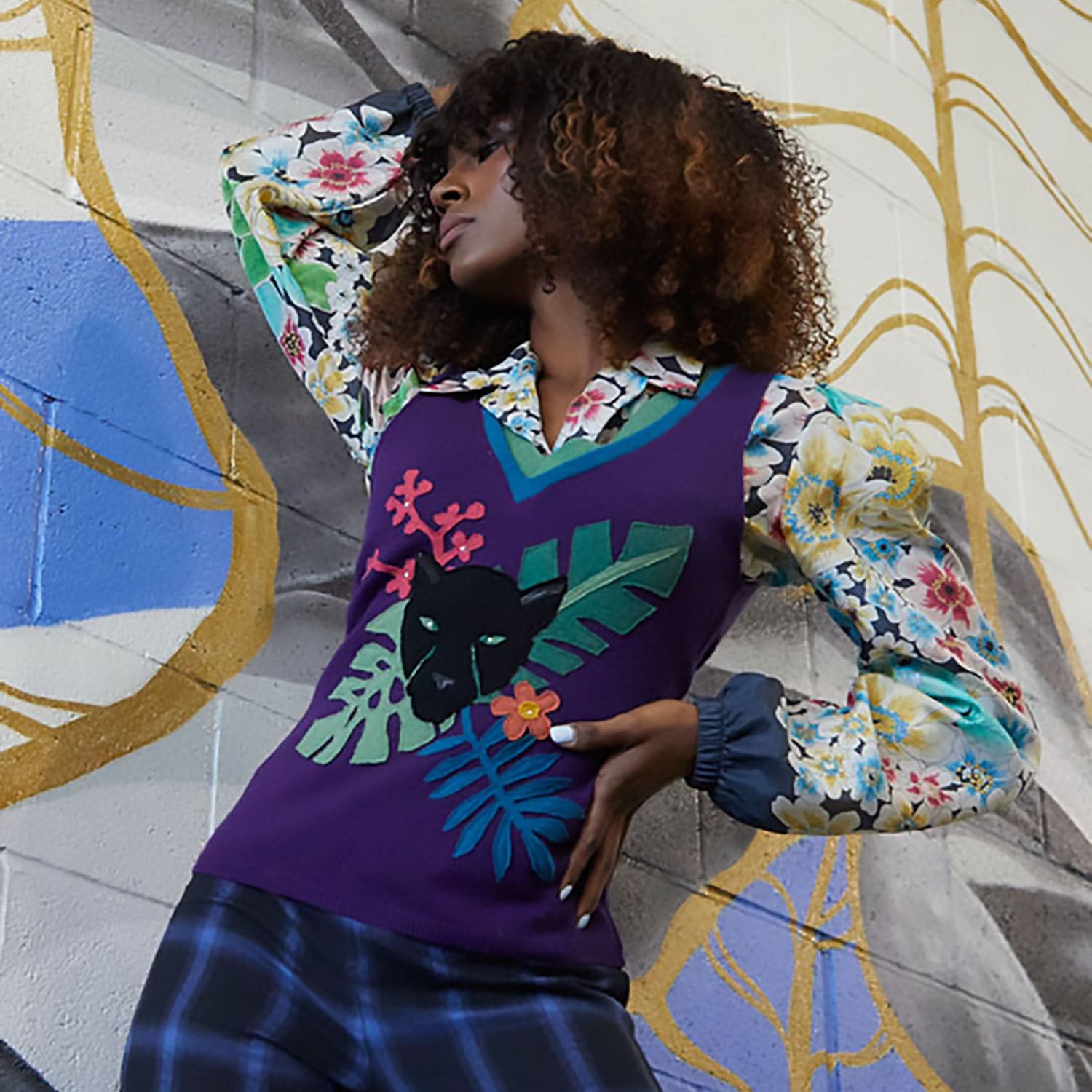 model in Purple upcycled cashmere sweater vest with green V-neck and black panther and jungle leaf appliqué design.