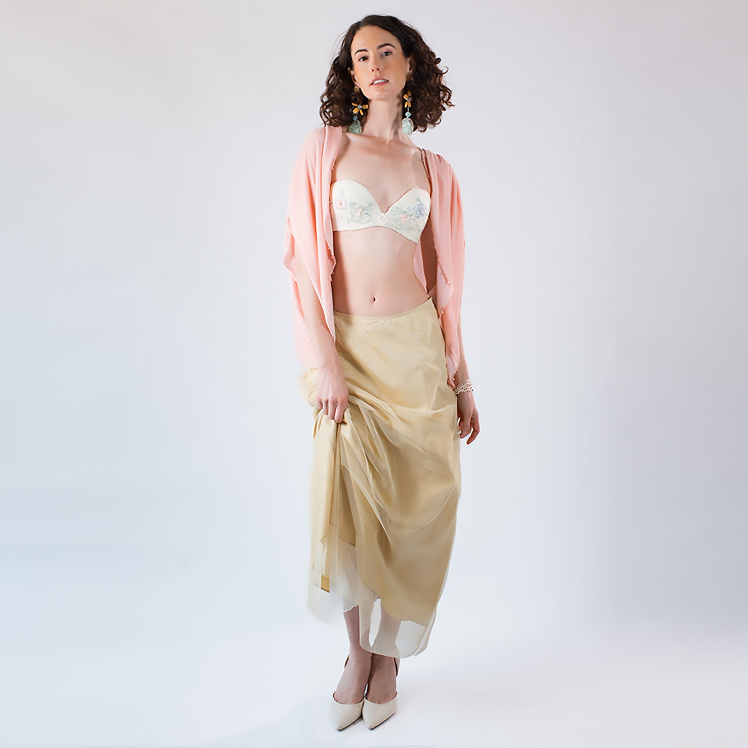 Model wearing a cream beaded strapless bustier styled with a blush velvet shrug and yellow silk skirt.