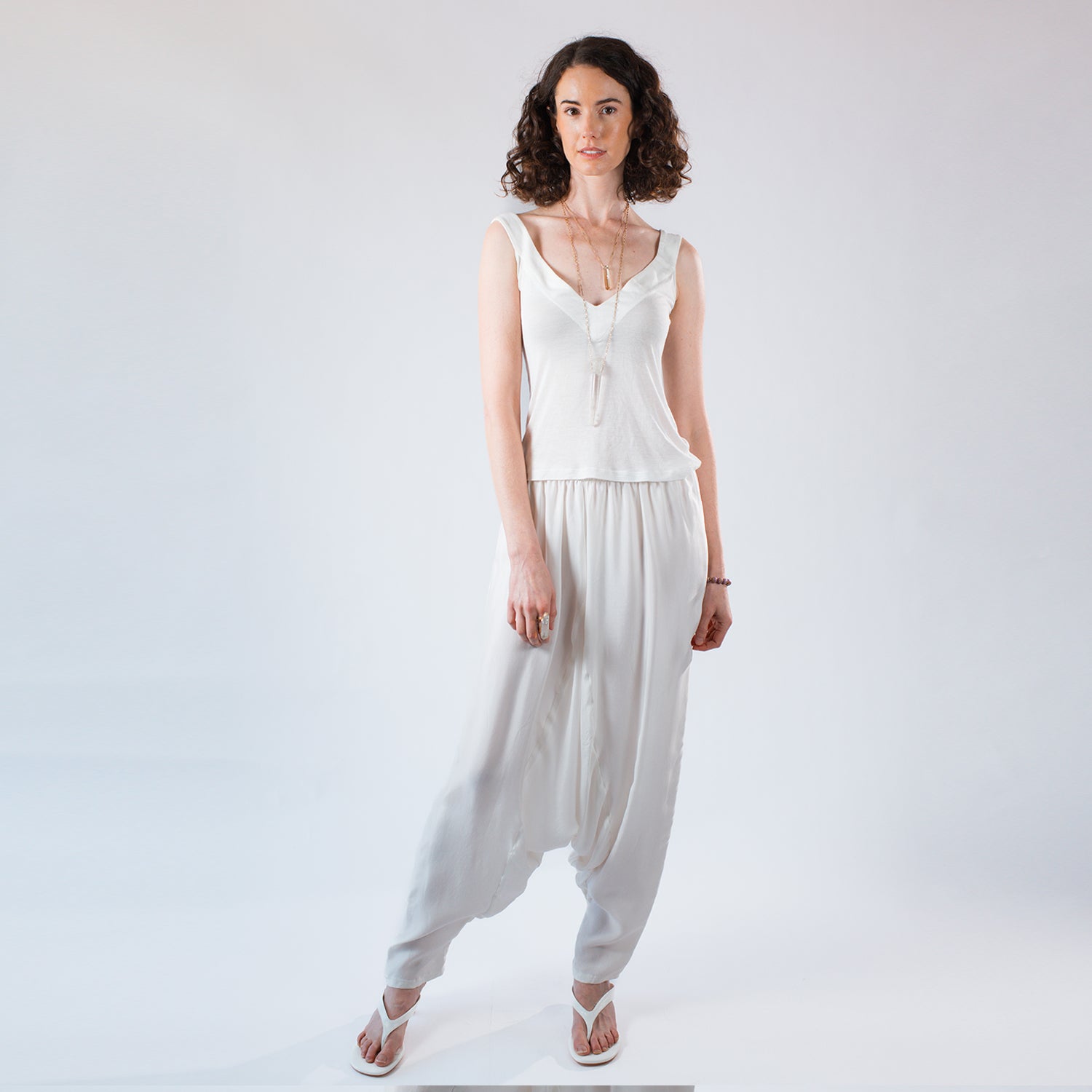 Model wearing fluid ivory rayon draped pants styled with an ivory modal tank top.