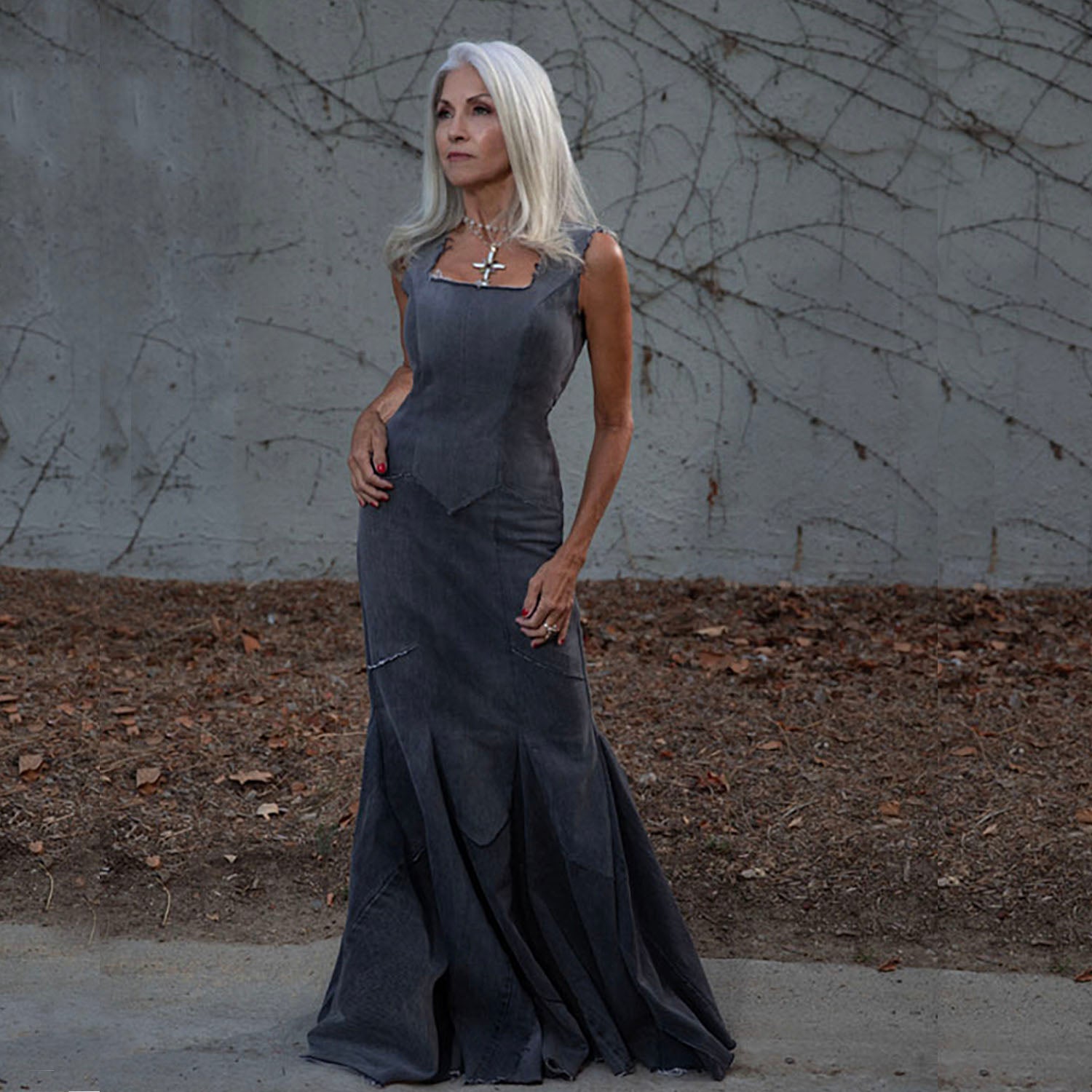 Diana Dress – sculpted mermaid gown in distressed black upcycled denim, raw-edged with exposed back zipper, worn by model outdoors.