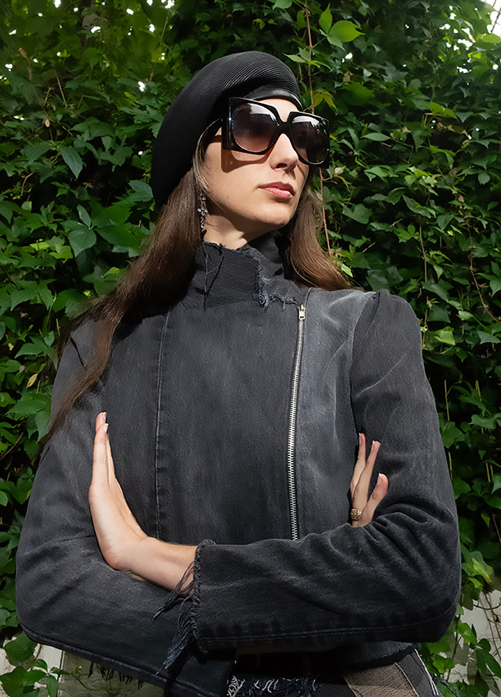 model in Angie Jacket in Distressed Black – upcycled black denim motorcycle jacket with raw edging and exposed zipper, one-of-a-kind wash and wear.