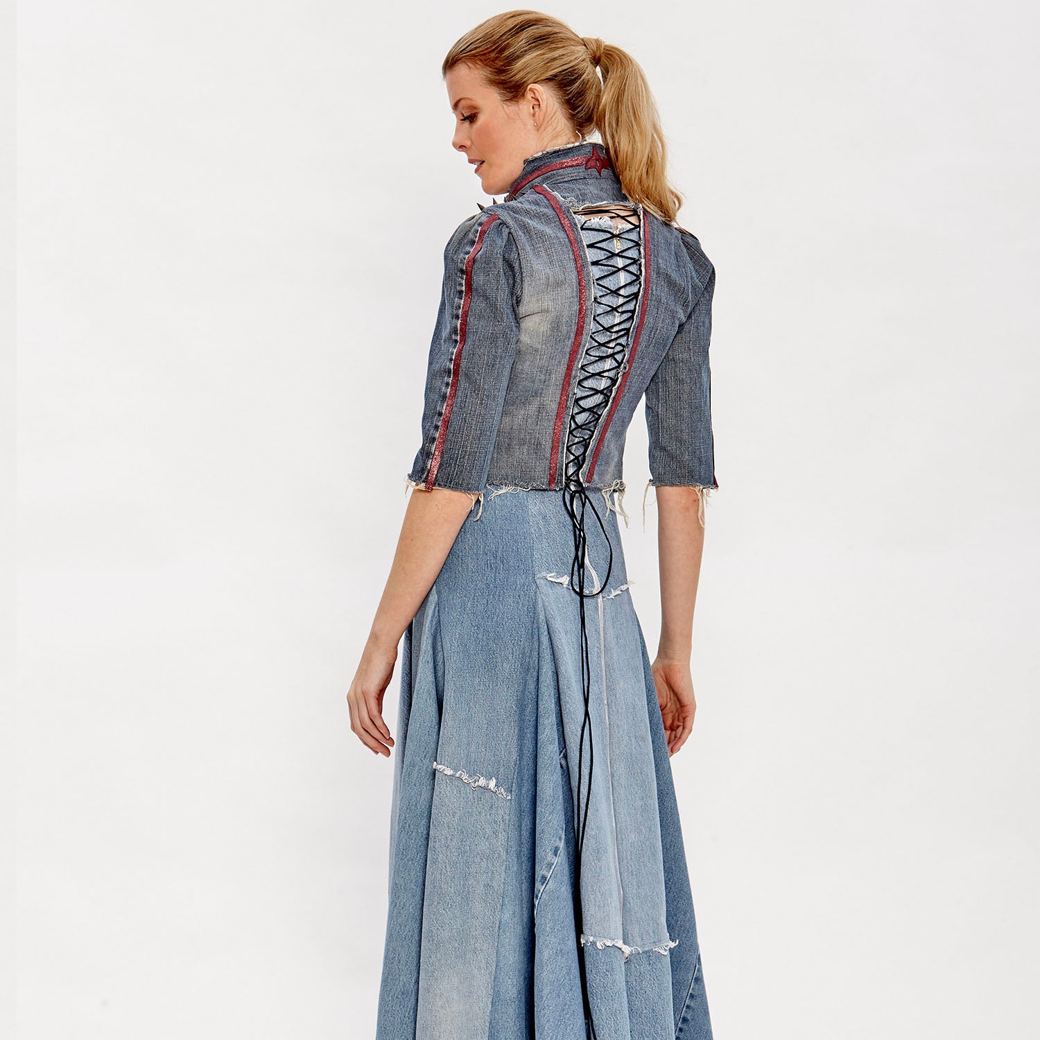model Gwendolyn Jacket – western-inspired cropped denim jacket with vintage leather appliqué, spike studs, and corset back, shown in dark upcycled wash.