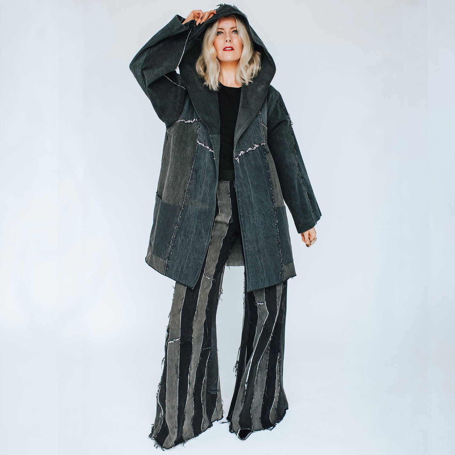 Oversized hooded black denim coat with raw-edge seams and a deconstructed silhouette.