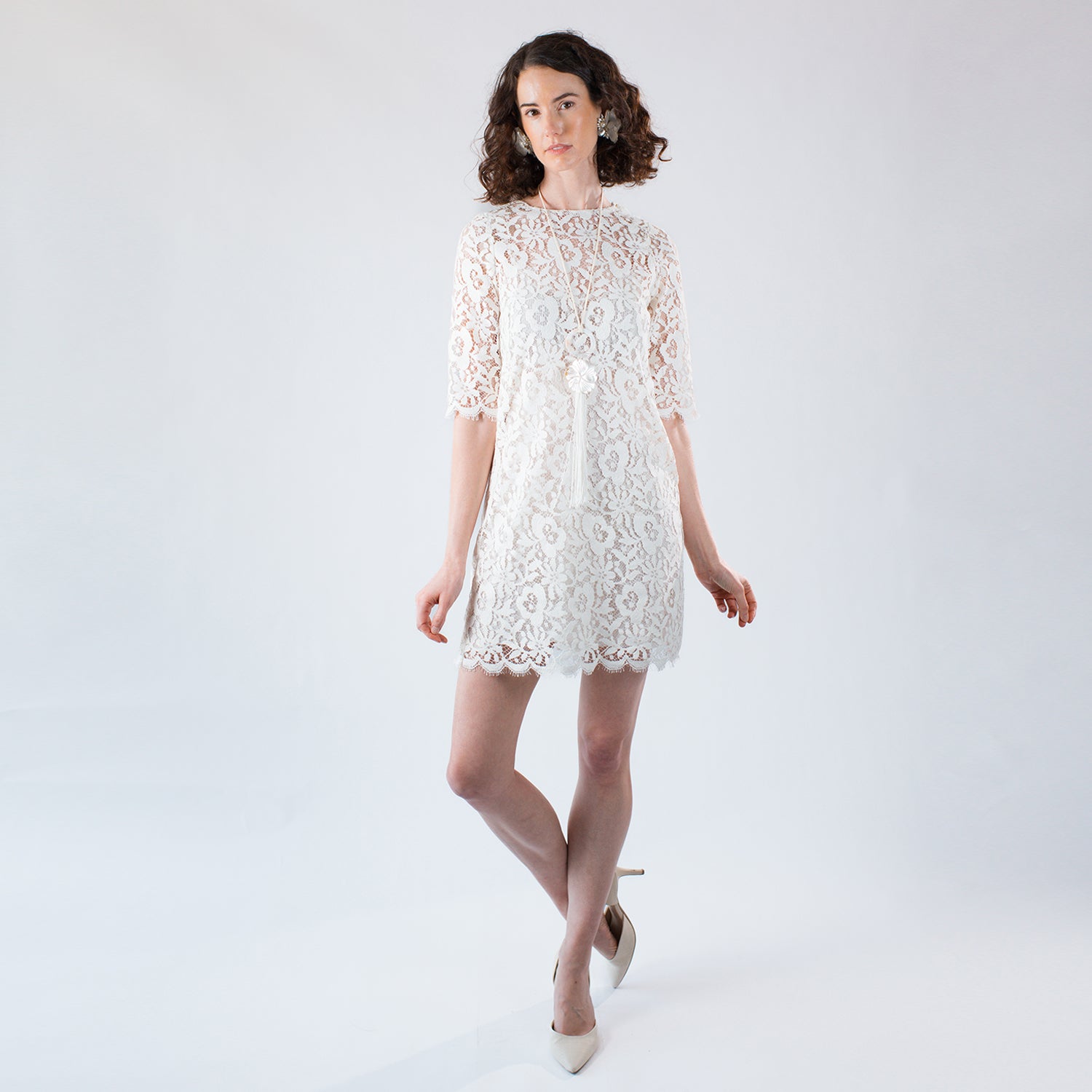 Model wearing an ivory cotton Chantilly lace shift dress with elbow-length sleeves.