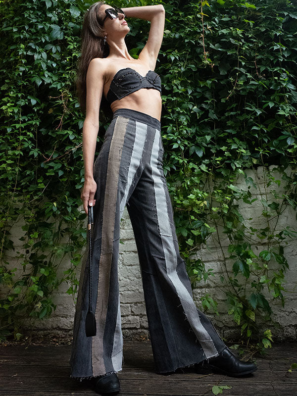 model in Layla Stripe Jean in black/grey upcycled denim with high waist, slim fit, and flared leg. Styled with cropped bralette outdoors.
