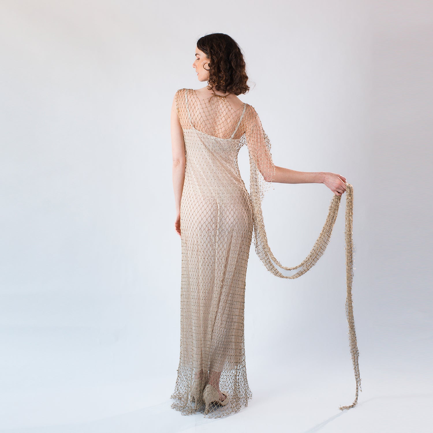 back Model wearing a hand-beaded dress created from retired fishing net layered over a slip dress.