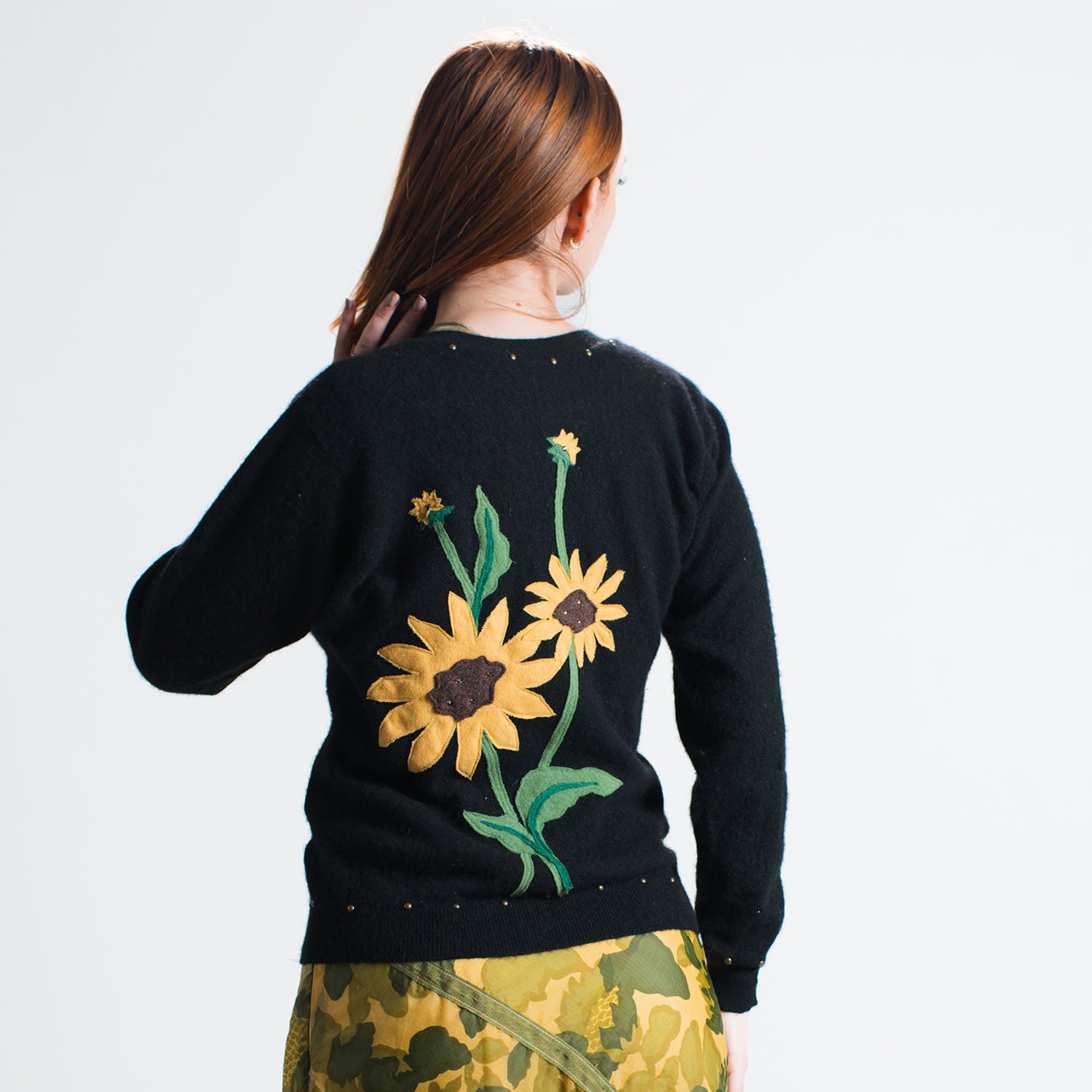 model back Sunflower Cardigan in black upcycled cashmere with floral appliqué at back,  metal buttons and brass studs