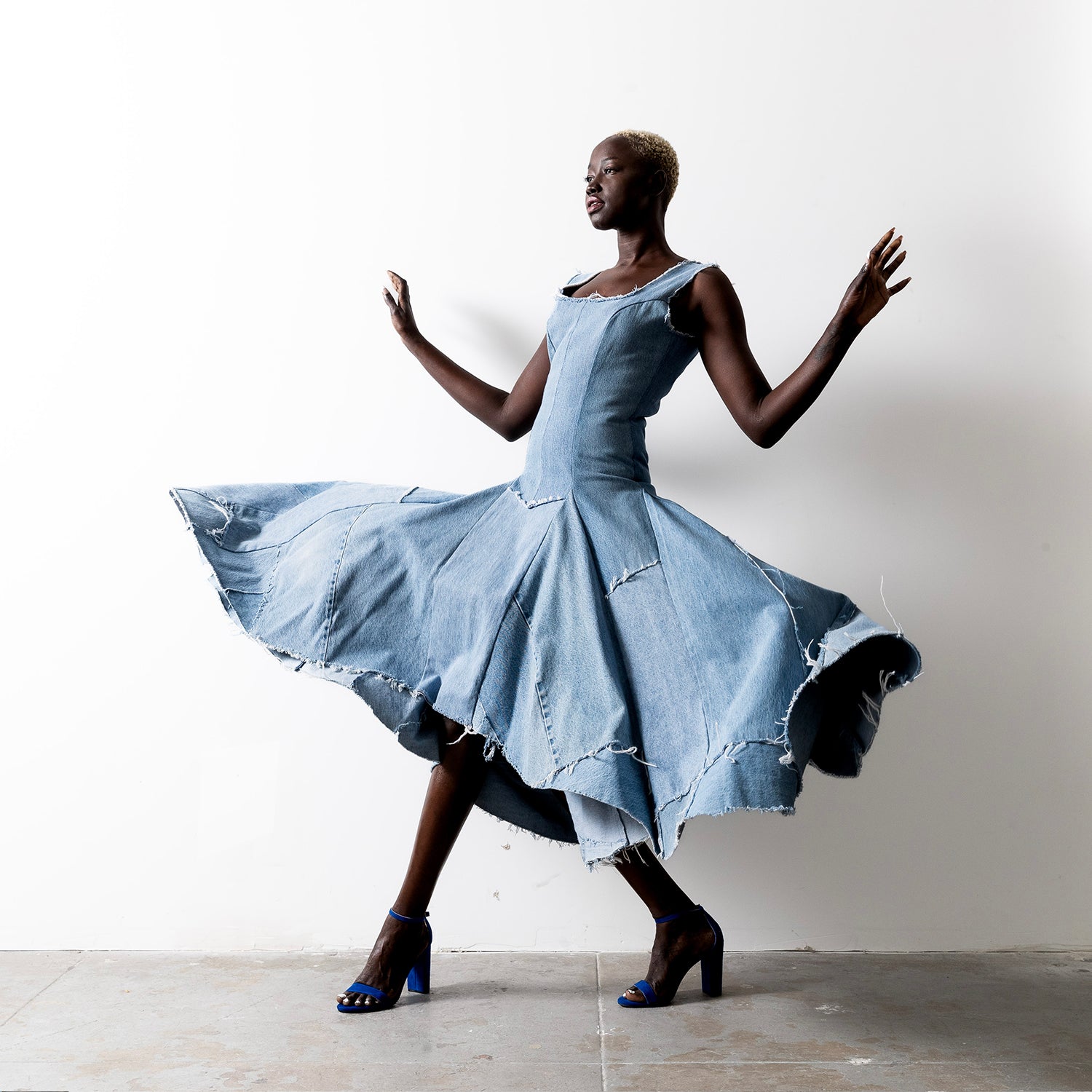 Valerie Dress in bleached denim – Valerie Dress in bleached denim – model twirling in high-low hem dress with dramatic movement and raw-edged finish.
