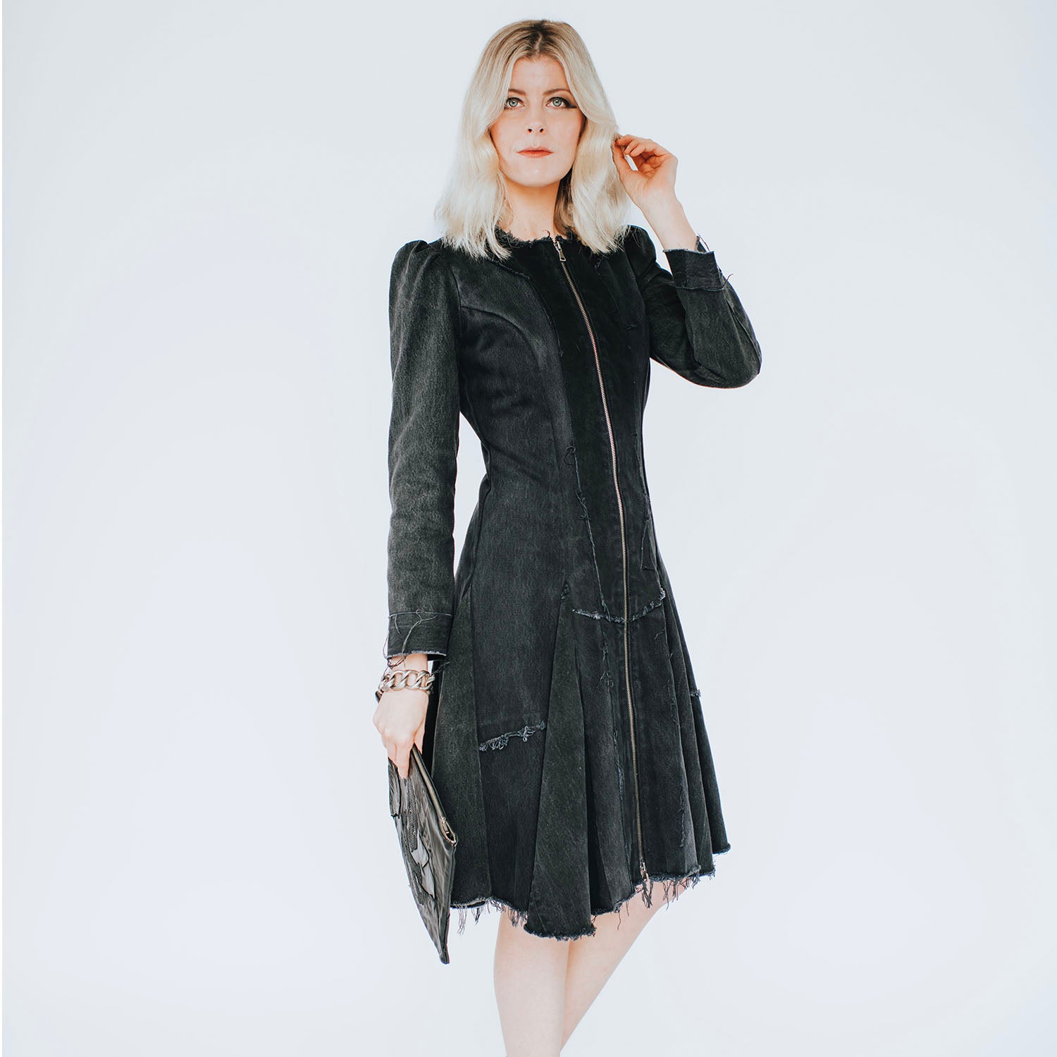 model in Front view of the Zelda Coat in distressed black denim featuring a fit-and-flare silhouette with raw-edged detailing and a full-length zipper closure.