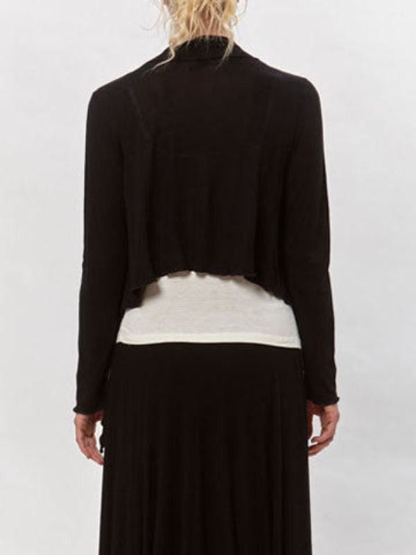 Model wearing the Jenna Flutter Front Wrap in black over a white tank and black skirt. Lightweight, draped open-front cardigan.