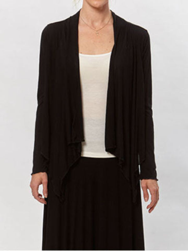 Model wearing the Jenna Flutter Front Wrap in black over a white tank and black skirt. Lightweight, draped open-front cardigan.